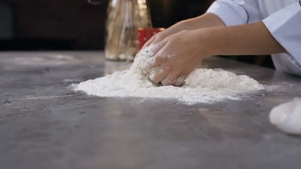 Mujer manos amasando masa mientras mezcla agua con harina en la mesa . — Vídeos de Stock