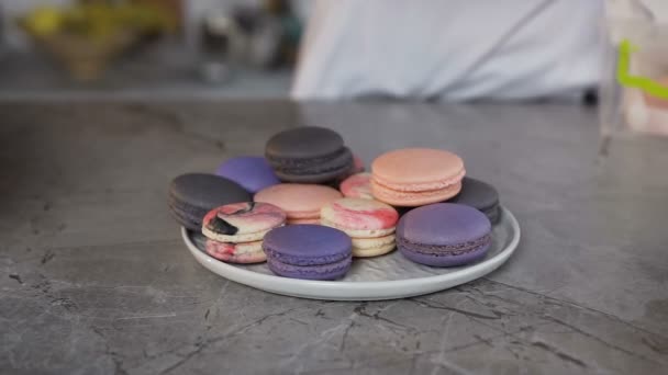 Female baker putting halves of macaroon into the plate. — Stock Video