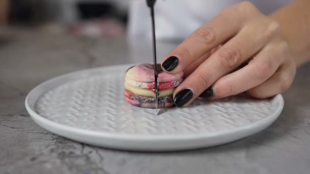 Nära upp skott av kvinna händer skära macaroon på halvorna med kniv. — Stockvideo