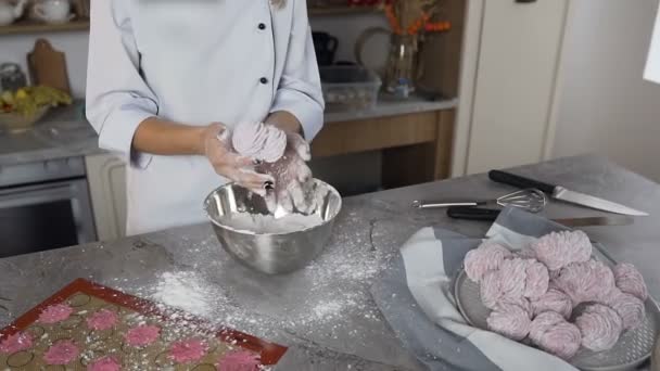 Pastelero joven rociando azúcar en polvo sobre malvavisco rosa . — Vídeos de Stock