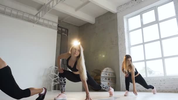 Groep van jonge vrouwen voeren warming-up in het fitnesscentrum. Fitnesstraining. Young Sport vrouwen in zwarte sport bodysuits fitness oefeningen uitvoeren. Gezonde levensstijl — Stockvideo