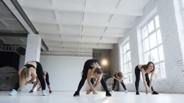 Bir parlak fitness merkezinde bir fitness sınıfta egzersiz siyah bodysuits, genç erkeklerde uygundur. Güzel kadınlar atletizm spor ve sağlıklı bir yaşam tarzı yapmak