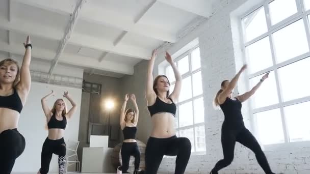 Unga attraktiva kvinnor gör varma i aerobics klass, fitness flickor utför steg utfall motion. Sport och hälsosam livsstil — Stockvideo