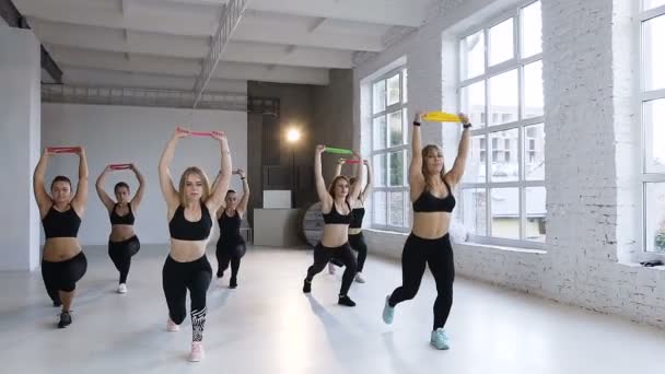 Eine Gruppe junger Sportlerinnen turnt mit Stepper in der Turnhalle. Cardio-Step-Dance, Instruktor mit Personengruppe beim Fitness-Studio-Training. Konzept von Sport, Training, Fitness-Kurs und gesund — Stockvideo