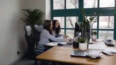 Ofiste bilgisayar üzerinde çalışan beyaz kadınlar.