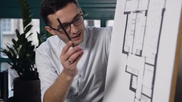 Jonge mannelijke ontwerpingenieur werken aan het project op de office-achtergrond. — Stockvideo
