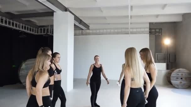 Group of young sporty people celebrating the end of a coaching giving friends a high five with bottles of waters. Smiling women holding water bottle, knock water bottles after workout in the gym — Stock Video