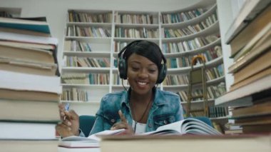 Afrikalı kız öğrencinin ders dinleme müzik süre yazma.