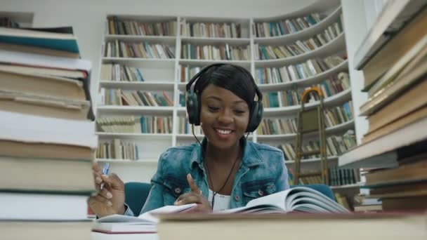 Studentessa africana che scrive lezione ascoltando musica . — Video Stock