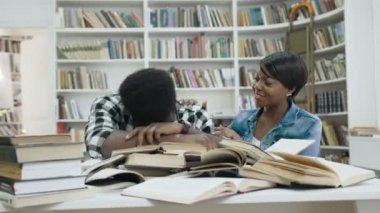 Modern kütüphanede onu uyandırmak Afrikalı genç kadın ise kitap üstünde uyumak yorgun Afrika genç adam.