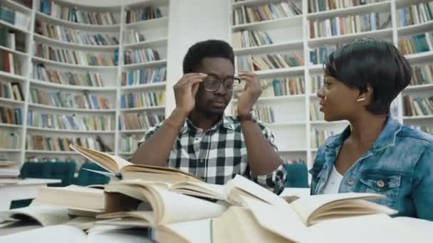 Αφρικανική φοιτήτριας διαβάζοντας το βιβλίο ενώ κουρασμένος αφρικανική αρσενικό φοιτητής στον ύπνο για τα βιβλία, ξυπνώντας τον επάνω. — Αρχείο Βίντεο