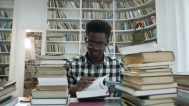 Kütüphanede otururken kitap okuma bardaklarda Afrika genç adam portresi.