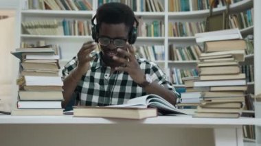 Stresli Afrika Genç kulaklık okuyan adam ve şık kütüphanede bağırmaya başlıyorsunuz.