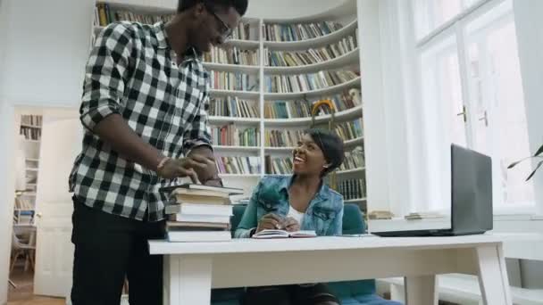 Cara africano caminhando para a biblioteca, dando cinco para menina africana atraente e começar a estudar juntos na biblioteca . — Vídeo de Stock