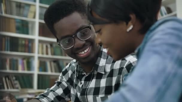 Unga afrikanska par förbereder examina i biblioteket. — Stockvideo