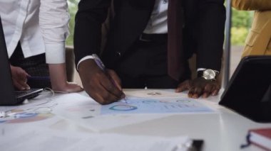 Yakın çekim. İş adamları veri çalışma ve yapmak grafikler analiz bir iş planı tartışıyor. Belge ve Ofis İşyeri kavram grafiklerde çalışma mutlu çok etnik iş adamları