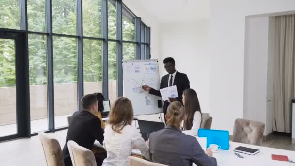 非洲经理在白板上向同事们介绍新的项目计划 向同事们解释新的想法 商人做介绍 与他们讨论想法 — 图库视频影像