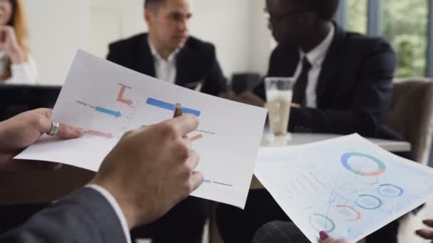 Detail ruce k nepoznání podnikatelů hledá prostřednictvím dokumentů s grafy a grafy na setkání s kolegy v moderní kanceláři. Koncepce činnosti