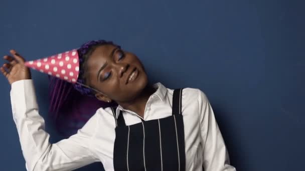 Portrait of beautiful african girl in birthday hat dancing on the blue background. — Stock Video