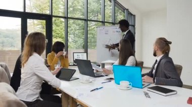 Flipchart üzerinde diyagramı çizme ve sunuyu Office Kurumsal Eğitim iş arkadaşları için parka panoramik pencereli holding african american adam