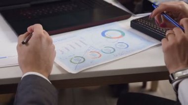 Yakın çekim bir konferans için günlük iş planları kullanımı belge ve grafikler tartışırken masanın iki beyaz genç iş adamları