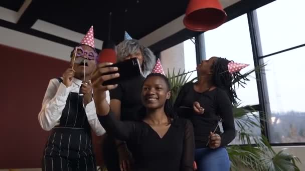 Hermosas cuatro chicas africanas posando en la cámara del teléfono inteligente mientras toma fotos durante la fiesta de cumpleaños . — Vídeos de Stock