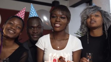 Genç mutlu Afrika kadın doğum günü pastası ile arkadaşları doğum günü partisi sırasında çevrili..