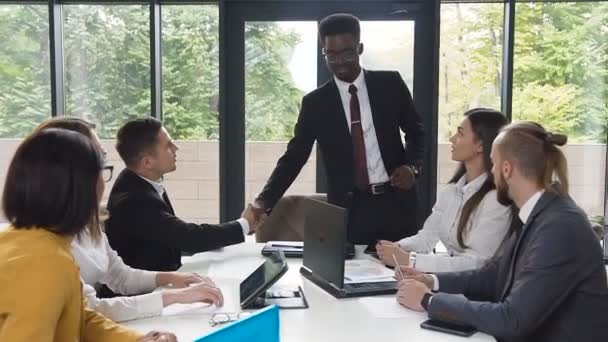 Empresário afro-americano bem sucedido está na sala de reuniões do escritório com colegas caucasianos, homem negro faz apertar as mãos durante uma reunião com colegas. Dolly atirou — Vídeo de Stock