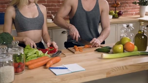 Dolly tiro de mãos masculinas cortando cenoura e mãos femininas cortando pimenta na placa de corte de madeira na cozinha . — Vídeo de Stock