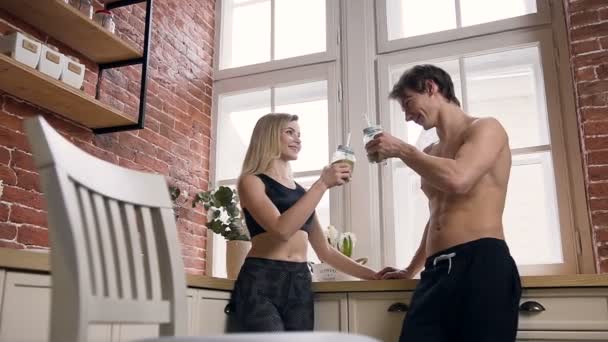 Atrakcyjna kobieta fit i człowiek pić koktajle w kuchni. — Wideo stockowe