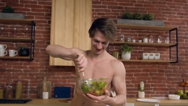 Happy fit man cooking salad in the kitchen. — Stock Video