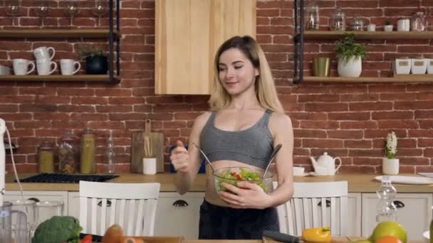 有吸引力的适合女孩与绿色沙拉在碗在厨房. — 图库视频影像