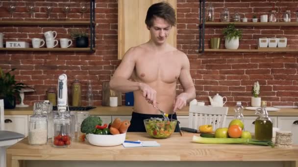 Hombre guapo ajuste cocina ensalada en la cocina . — Vídeo de stock