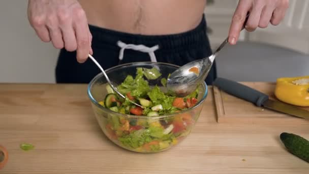 Gros plan des mains de l'homme mélangeant la salade . — Video