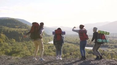 Hipsters turist sırt çantaları ve giysileri ile bir grup sıçrayan ve yüksek dağlar ve harika doğa fonunda sevindirici. Başarı ve üst fethi kavramı.