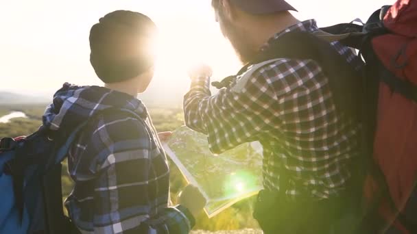 Arkadan Görünüm. Sırt çantaları ve turist Haritası, yön bulmaya çalışırken dağlara yolculuk hiking zevk dağın tepesinde duran genç çiftin yakın çekim — Stok video