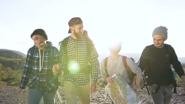 Portrait - Groupe de quatre amis voyageurs marchent avec la carte en essayant de trouver le bon chemin sur le sommet de la montagne au coucher du soleil, rire et parler. Tourisme et mode de vie sain concept. Dolly shot — Video