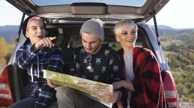 Harita iki genç kadın ve kullanan bir adam arabanın bagajında otururken doğru yol aramak için.