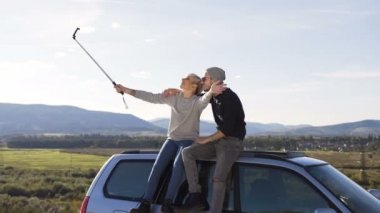 Selfie akıllı telefonda yapma, araç dağ zemin üzerine çatı üzerinde oturan genç hippi çift.
