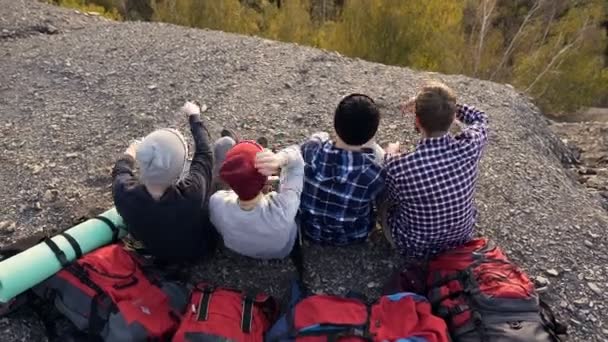 Vista superior de cuatro amigos cansados tumbados en la mochila en el suelo en la montaña . — Vídeo de stock