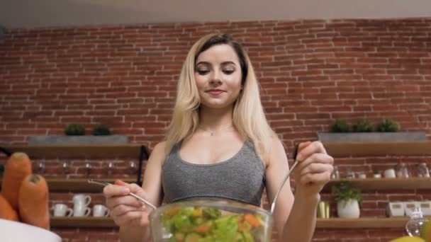 Молодая пригодная женщина готовит веганский салат из свежих зеленых овощей с использованием оливкового масла после тренировки. Концепция здорового питания — стоковое видео