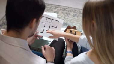 Gelecekteki ev tartışırken blueprint ve ev modeli genç Çift.