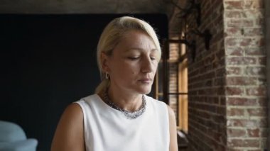 Güzel Olgun kadın mutlu bir ifadeyle dışında pencereden bakarak yakınındaki kahve oturma içiyor. İş kadını kahve kahve arası iş yaparken keyif alıyor