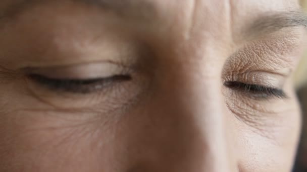 Primer plano de la cara de las mujeres maduras caucásicas con ojos oscuros y arrugas visibles de envejecimiento — Vídeo de stock