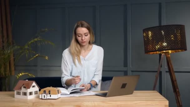 Blonda femeie agent imobiliar notând unele idei în notebook . — Videoclip de stoc