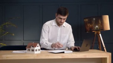 Erkek ciddi emlakçı Notebook dizüstü bilgisayarda bazı notu oluşturma.