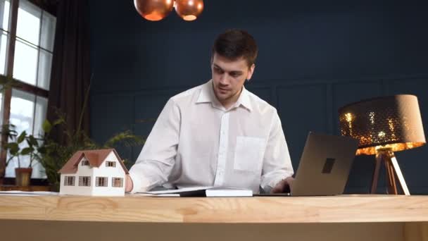 Jonge mannelijke architect werkt op de nieuwe ontwerpen van huis met behulp van 3D-model van het huis. — Stockvideo