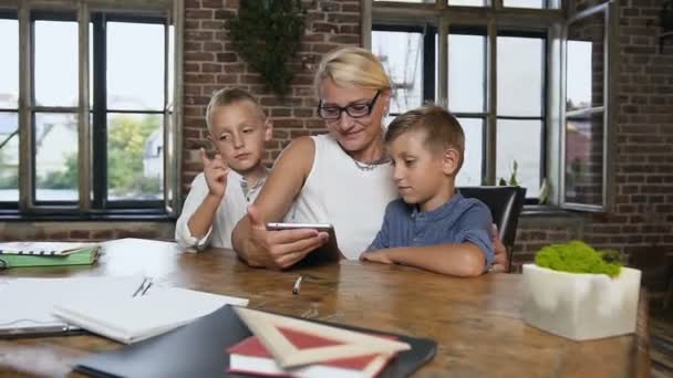 Kaukaski kobieta w średnim wieku w okularach wykonywanie ćwiczeń z dwóch uczniów na tablecie, szczęśliwy chłopcy z babcią używa gadżet z przyjemnością kryty, strzał w stylowe biuro pokoju w domu — Wideo stockowe