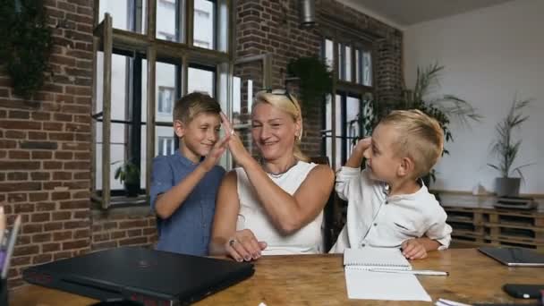 Die zufriedene Lehrerin mittleren Alters und ihre kleinen Schüler, die sich über den Abschluss des Unterrichts und die Hausaufgaben freuen, reichen sich in der Klasse der Grundschule gegenseitig Palmen. — Stockvideo