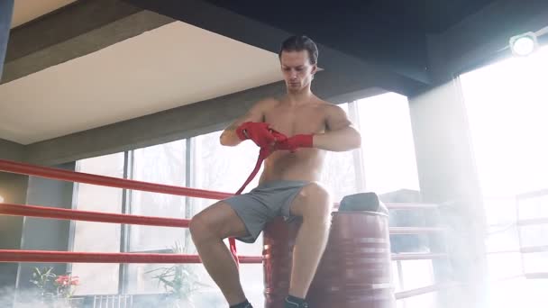 Young man boxer wrapping red bandages in the gym. Stock Footage